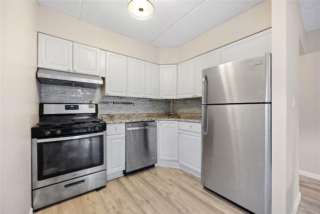 kitchen with white cabinetry, light stone countertops, stainless steel appliances, light hardwood / wood-style flooring, and decorative backsplash