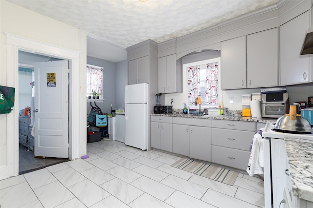 kitchen with gray cabinetry, white appliances, sink, light stone countertops, and a textured ceiling