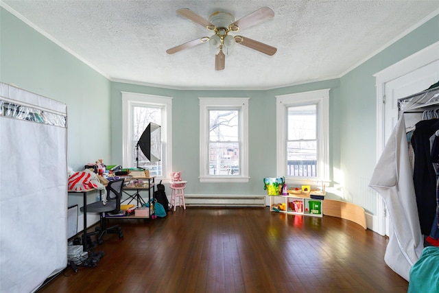 recreation room with a textured ceiling, ceiling fan, dark hardwood / wood-style floors, and a baseboard heating unit