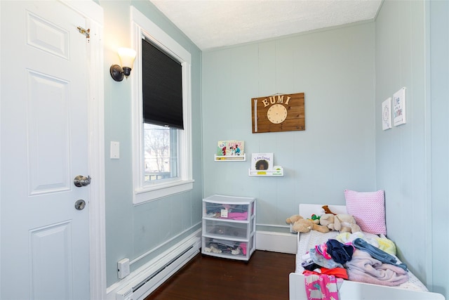 bedroom with dark hardwood / wood-style flooring and baseboard heating