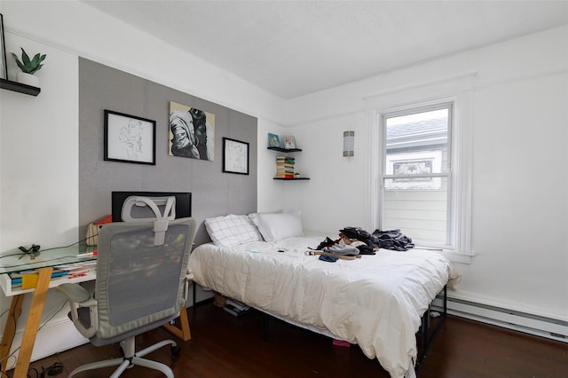 bedroom with dark wood-type flooring and a baseboard heating unit