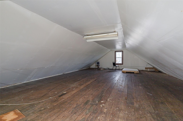 additional living space featuring dark wood-type flooring and vaulted ceiling