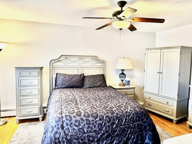 bedroom with baseboard heating, ceiling fan, and light hardwood / wood-style floors