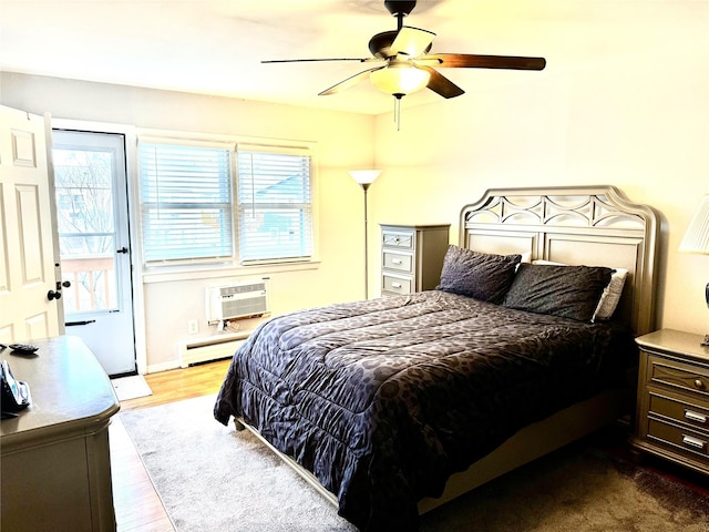 bedroom with a wall mounted AC, ceiling fan, hardwood / wood-style floors, and a baseboard heating unit