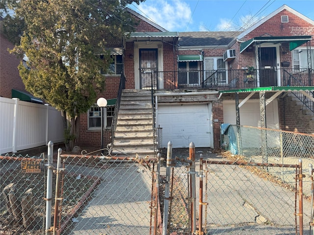 view of front of home with a garage and a wall mounted AC