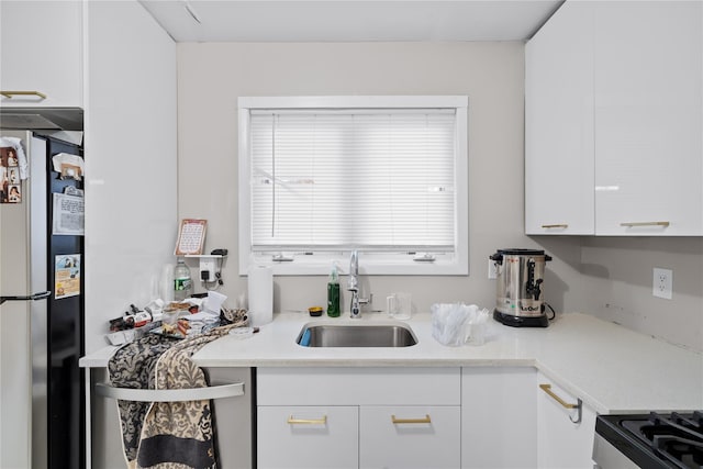 kitchen featuring white cabinets, stainless steel fridge, range with electric stovetop, and sink