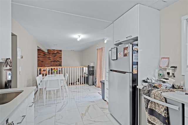 kitchen featuring stainless steel refrigerator and white cabinetry