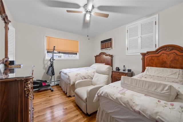 bedroom with a wall mounted air conditioner, ceiling fan, light hardwood / wood-style floors, and a baseboard radiator