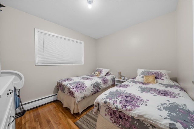 bedroom featuring wood-type flooring and a baseboard heating unit