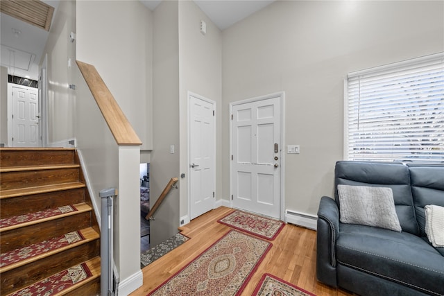 entrance foyer featuring a towering ceiling, light hardwood / wood-style flooring, and baseboard heating