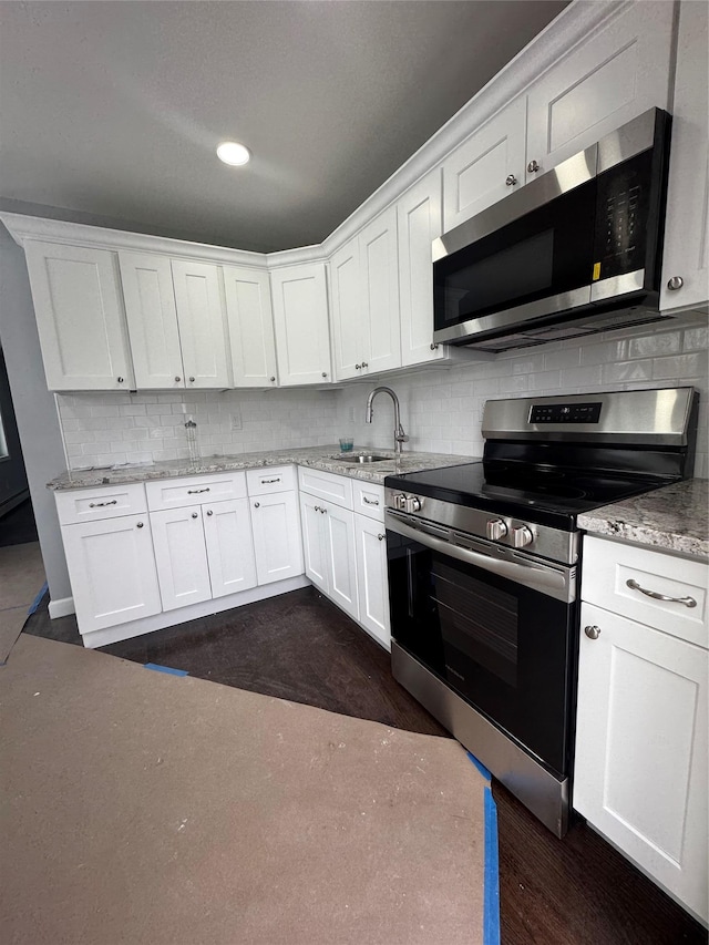 kitchen with sink, stainless steel appliances, tasteful backsplash, white cabinets, and dark hardwood / wood-style flooring