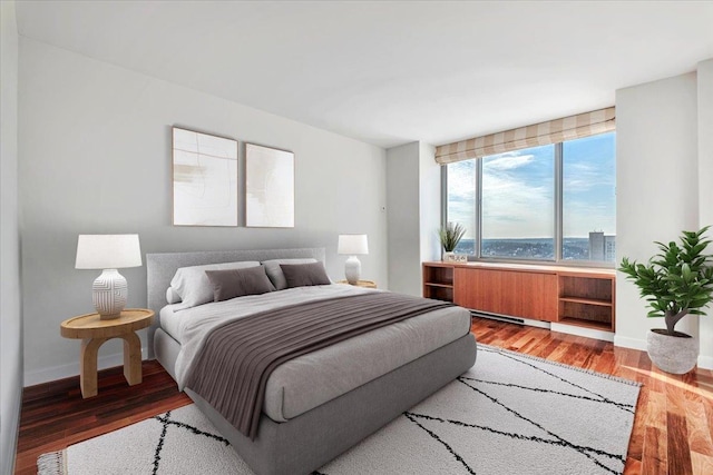 bedroom with hardwood / wood-style floors and a water view