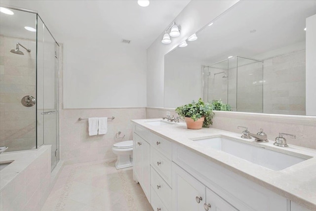 bathroom featuring tile walls, tile patterned flooring, vanity, walk in shower, and toilet