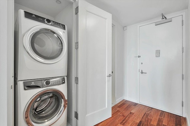 clothes washing area with laundry area, wood finished floors, and stacked washer and dryer