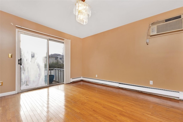 spare room with hardwood / wood-style flooring, a baseboard heating unit, a wall mounted air conditioner, and an inviting chandelier