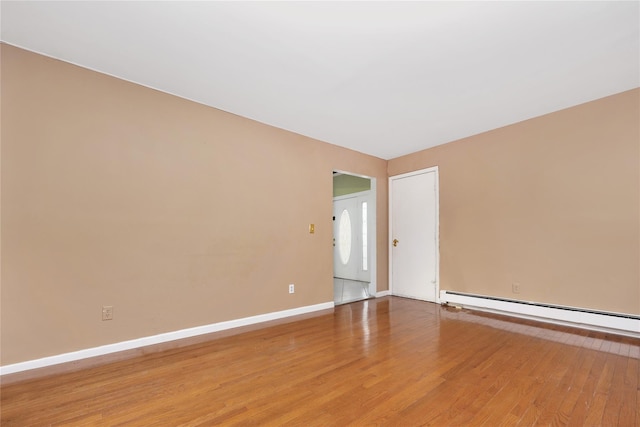 empty room featuring hardwood / wood-style floors and a baseboard heating unit