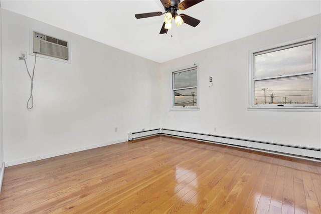 empty room with a wall mounted AC, light wood-type flooring, and ceiling fan