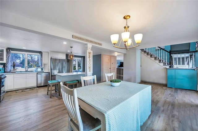 dining space with light wood-type flooring and an inviting chandelier