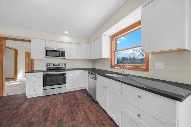 kitchen with white cabinets, sink, appliances with stainless steel finishes, and dark wood-type flooring