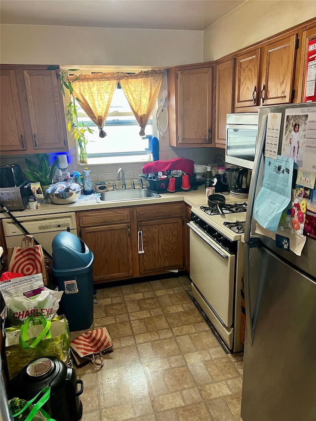 kitchen featuring stainless steel fridge, sink, and white range with gas cooktop