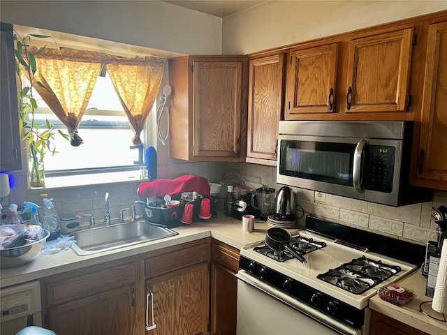 kitchen with backsplash, washer / clothes dryer, white gas range, and sink