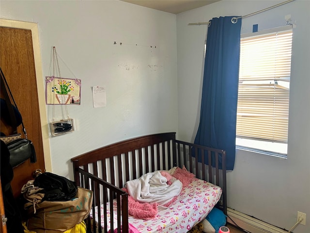 bedroom featuring a baseboard radiator and a crib