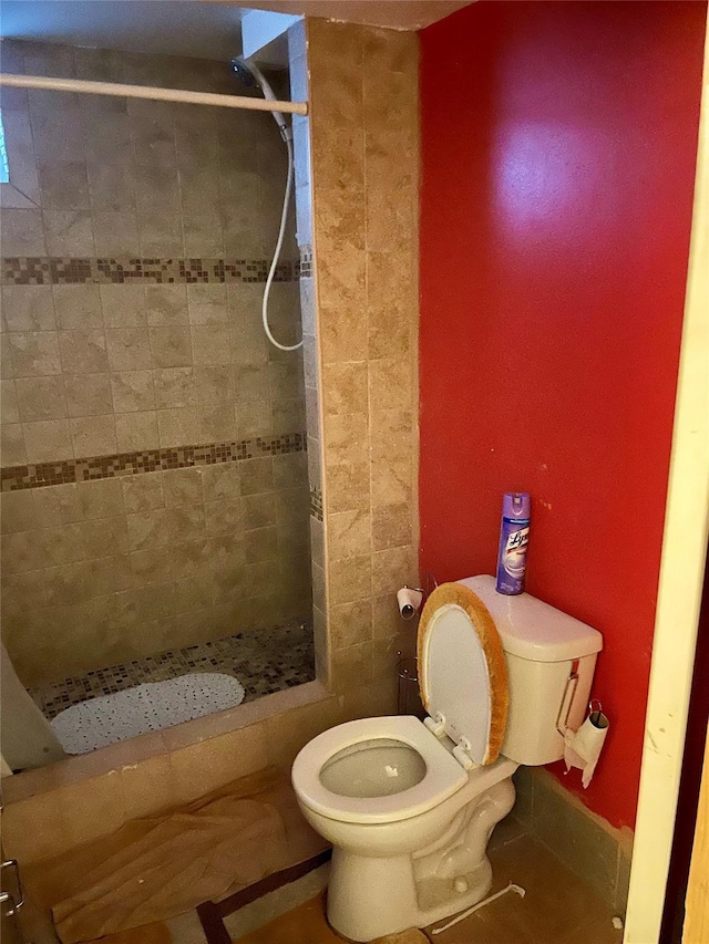 bathroom featuring a tile shower, tile patterned floors, and toilet