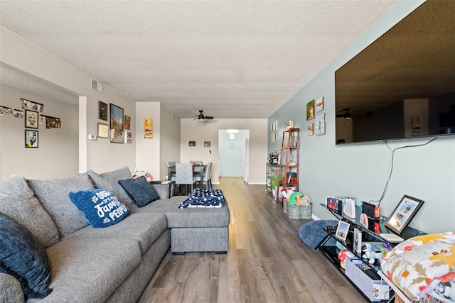 living room featuring wood-type flooring, a textured ceiling, and ceiling fan