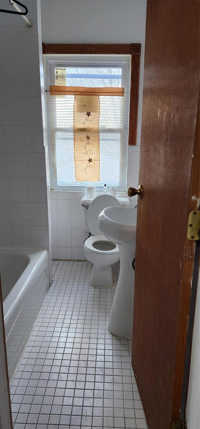 bathroom featuring tile patterned flooring, toilet, and tile walls