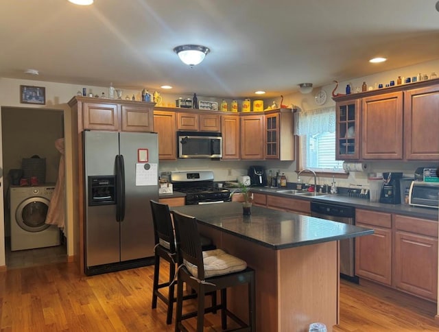 kitchen with a center island, sink, light hardwood / wood-style flooring, stainless steel appliances, and washer / clothes dryer