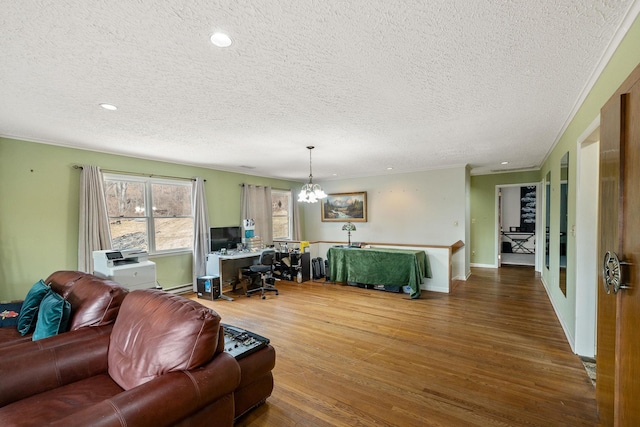 living room featuring hardwood / wood-style floors, a textured ceiling, a notable chandelier, and ornamental molding