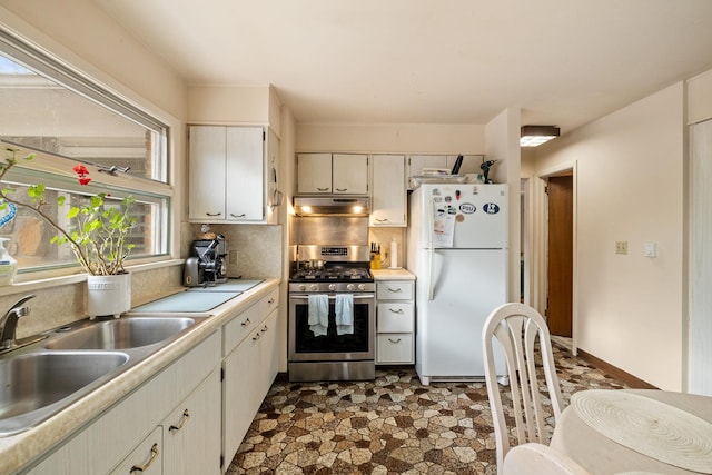 kitchen with stainless steel gas stove, sink, white refrigerator, and tasteful backsplash