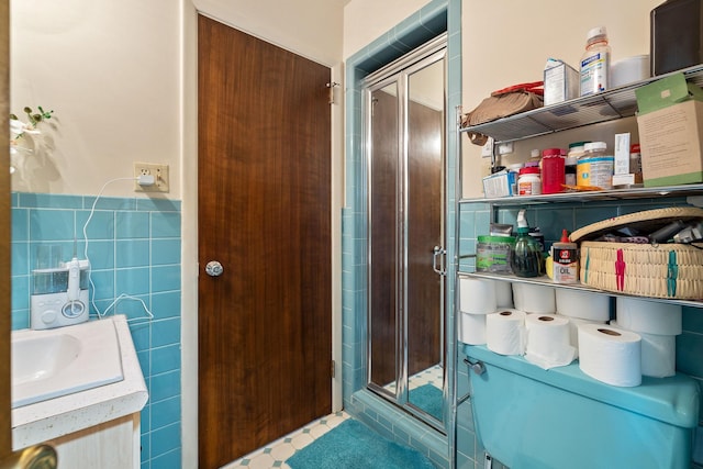 bathroom with a shower with shower door, tile walls, and vanity