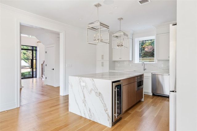 kitchen with pendant lighting, a kitchen island, white cabinetry, stainless steel appliances, and beverage cooler