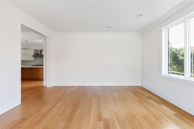 empty room with baseboards, ornamental molding, and light wood-style floors