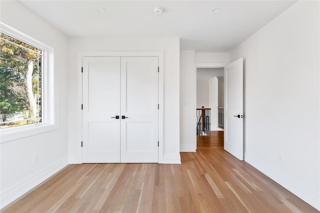 unfurnished bedroom with baseboards, light wood-style floors, and a closet