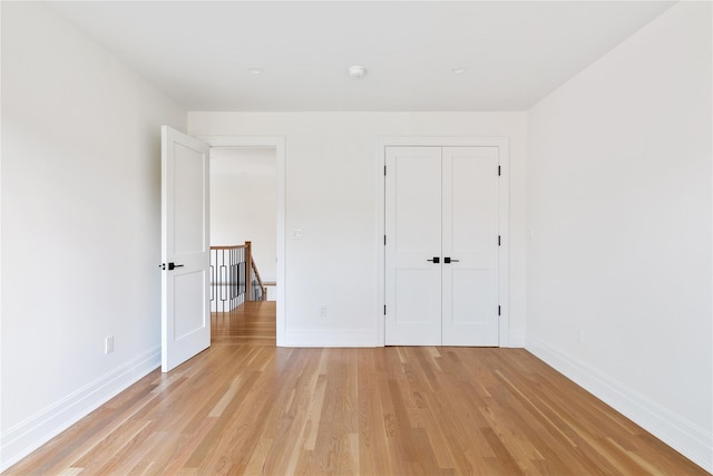 unfurnished bedroom with a closet, baseboards, and light wood-type flooring