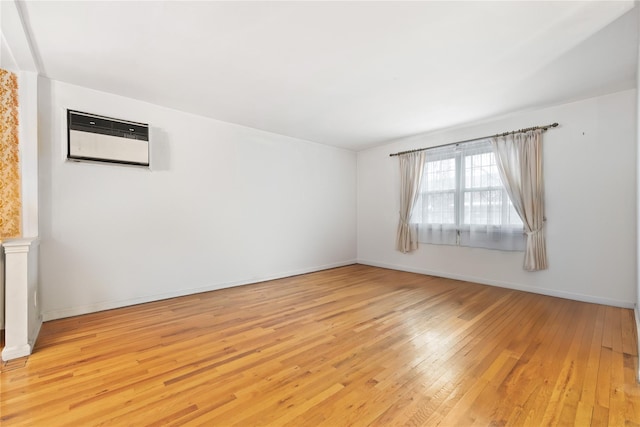 empty room featuring a wall mounted air conditioner and light wood-type flooring