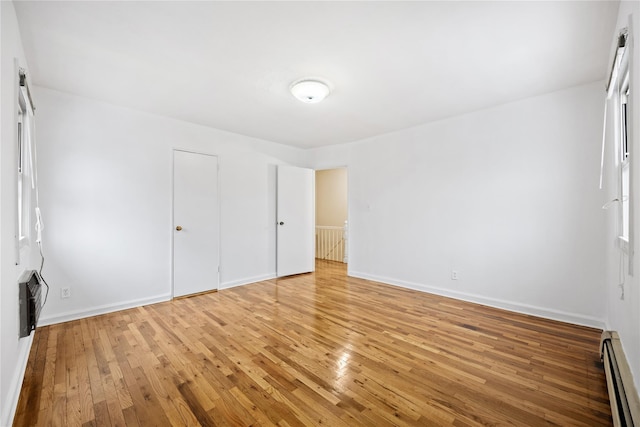 unfurnished bedroom featuring wood-type flooring, a closet, and baseboard heating