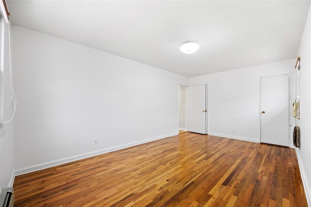 empty room featuring hardwood / wood-style floors and baseboard heating