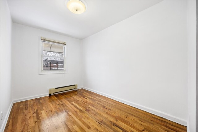 unfurnished room featuring a baseboard radiator and hardwood / wood-style flooring