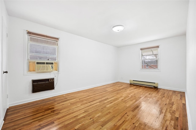 empty room with heating unit, hardwood / wood-style floors, cooling unit, and a baseboard radiator