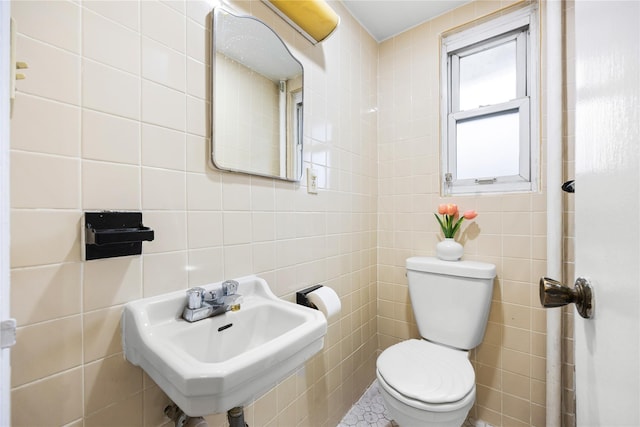 bathroom with toilet, sink, and tile walls