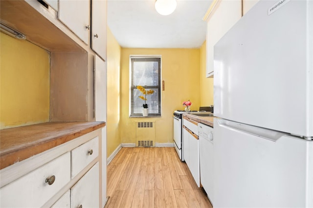 kitchen with radiator heating unit, white cabinets, light hardwood / wood-style floors, and white appliances