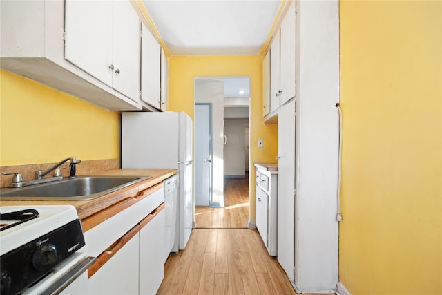 kitchen with white cabinetry, sink, white appliances, and light hardwood / wood-style flooring