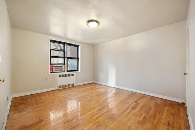 spare room featuring light hardwood / wood-style flooring, radiator, and cooling unit