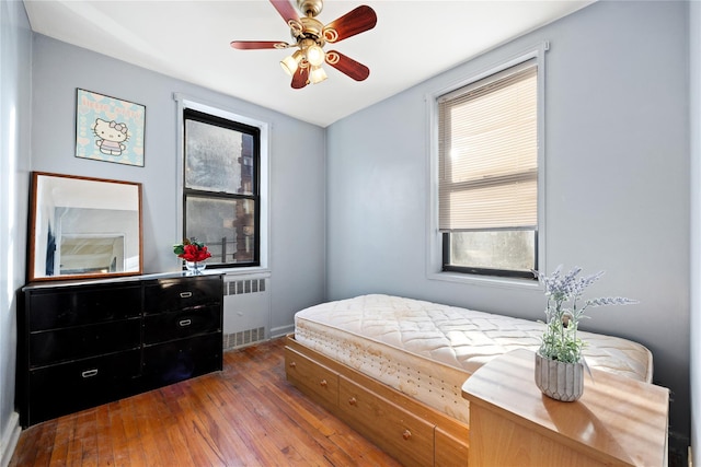 bedroom with radiator, dark wood-type flooring, and ceiling fan