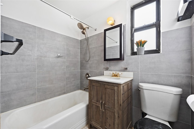 full bathroom featuring vanity, tiled shower / bath, tile walls, and toilet