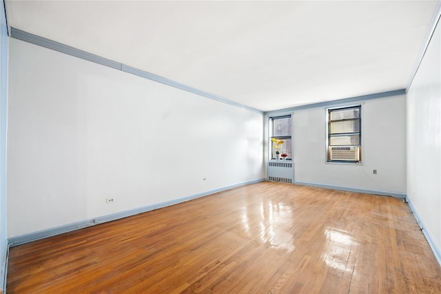 unfurnished room with radiator, light hardwood / wood-style flooring, cooling unit, and ornamental molding