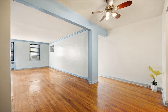 unfurnished room with ceiling fan, cooling unit, wood-type flooring, and radiator